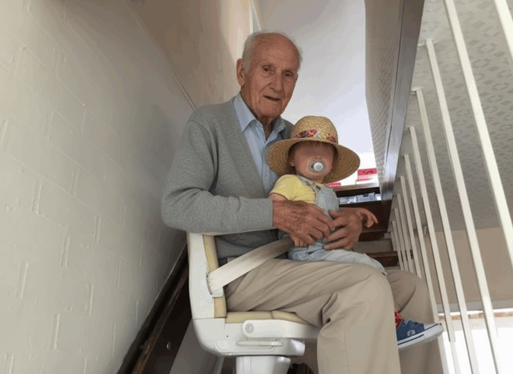 il signor Emiliano e il suo nipotino a bordo del montascale a poltroncina per scale dritte